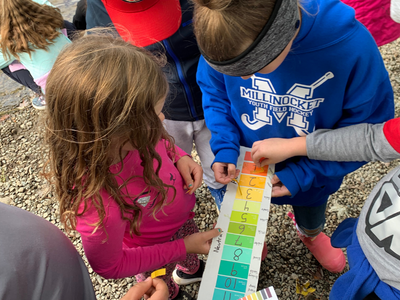 Children looking at a water test strip.