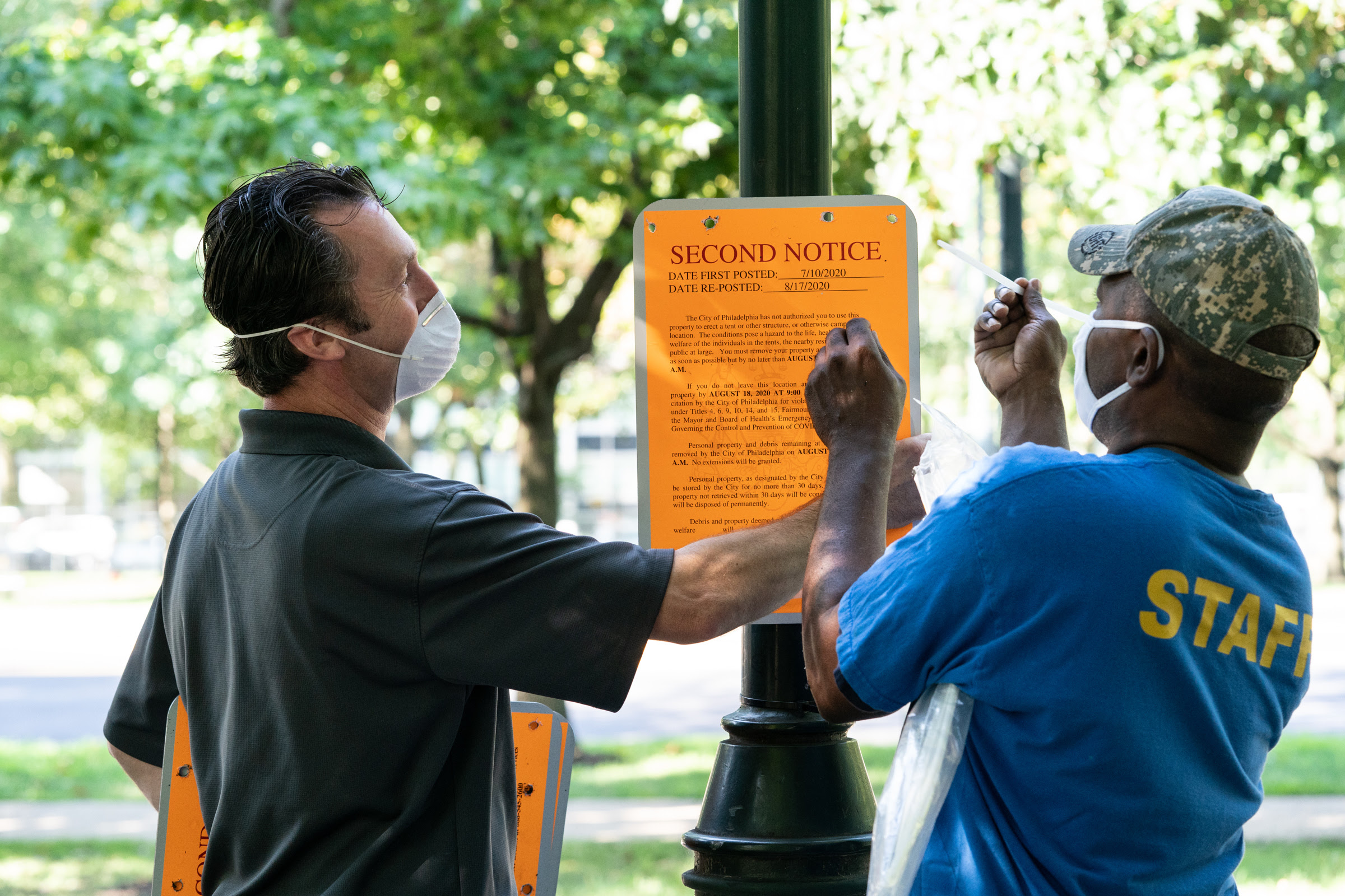 City employees post a second notice sign at the encampment at 22nd and the Parkway, August 17, 2020, in Philadelphia.