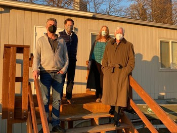 Photo of four people standing in from of a trailer