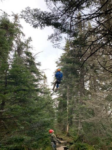 injured hiker gets lifted out as Forest Ranger supervises from below