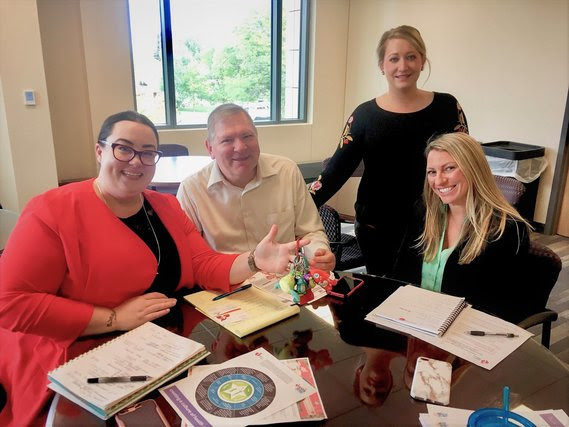 WDE staff wit with staff from the American Heart Association in a collaboration space at the WDE. One of them holds a keyring full of trinkets.