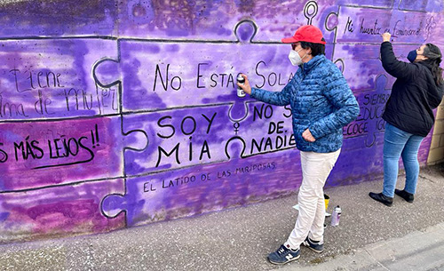 Mujer reralizando un grafitti durante la campaña de FADEMUR para marcar los pueblos contra la violencia machista antes del 8M.