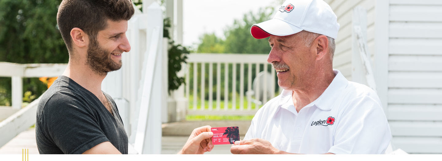 A veteran handing a Legion membership card to another person.