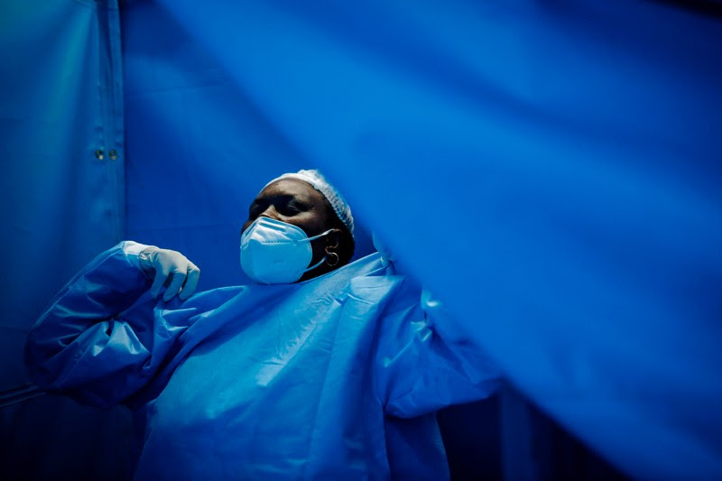 A nurse puts on her personal protective equipment