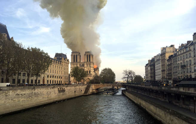 Slide 20 of 31: Notre Dame cathedral is burning in Paris, Monday, April 15, 2019. Massive plumes of yellow brown smoke is filling the air above Notre Dame Cathedral and ash is falling on tourists and others around the island that marks the center of Paris. (AP Photo/Lori Hinant)