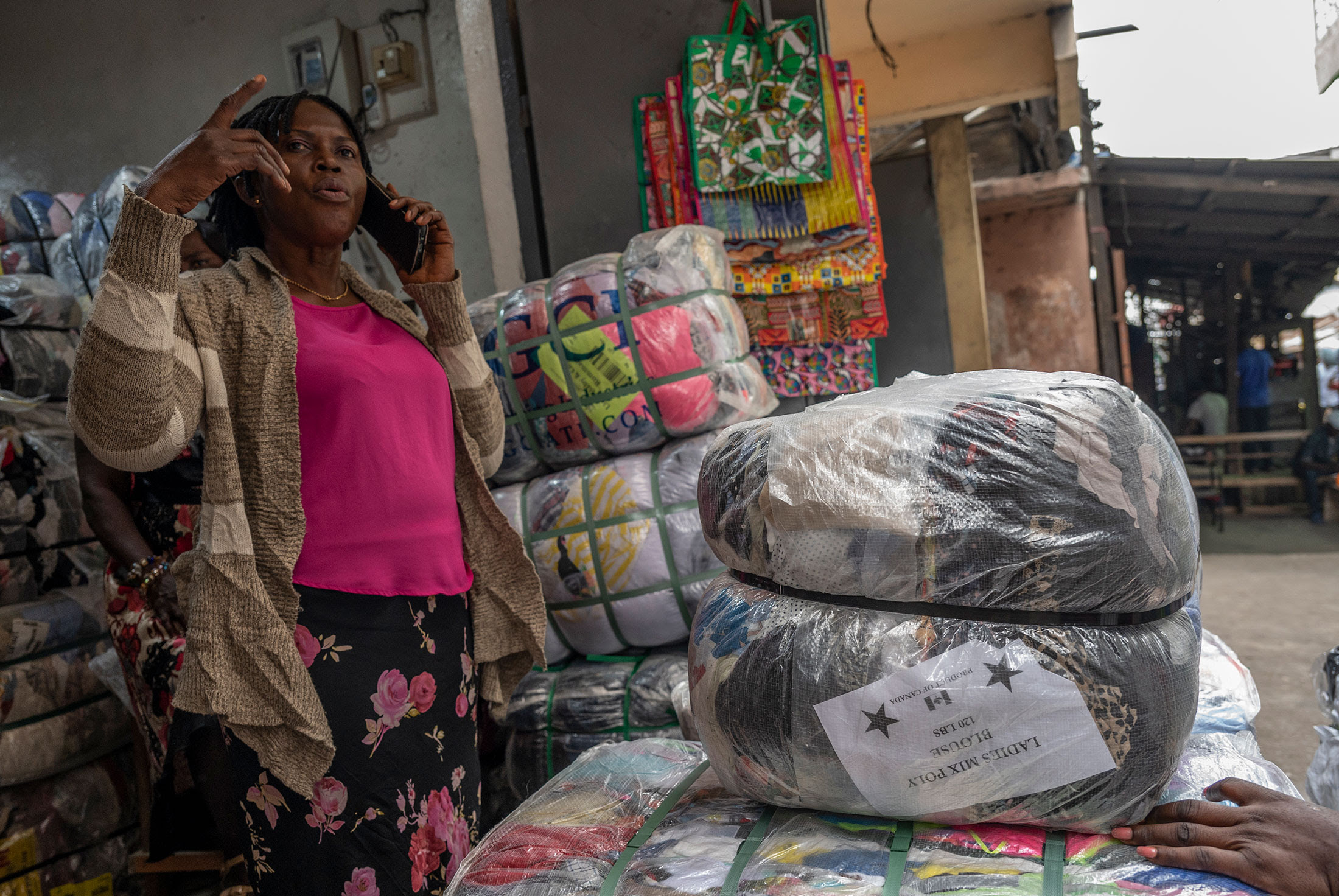 A seller speaks with a buyer as she tries to sell bales of secondhand clothing in Accra.