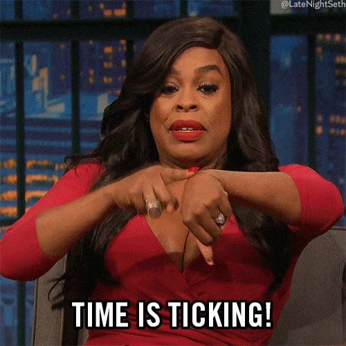 A gif of a woman in a red dress pointing repeatedly to her wrist with the words, “Time is ticking!”
