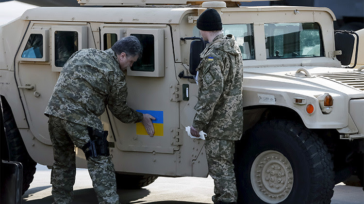 El presidente ucraniano, Piotr Poroshenko, pega una bandera nacional en uno de los vehículos entregados por EE.UU.