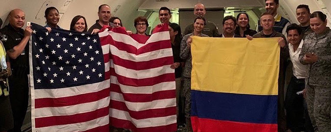 ASPR personal holding American flag standing next to Columbia officials holding Columbia Flag