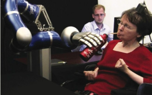 A participante no estudo S3 bebe com a ajuda do braço robótico comandado por seu cérebro (Foto: Divulgação/Nature)