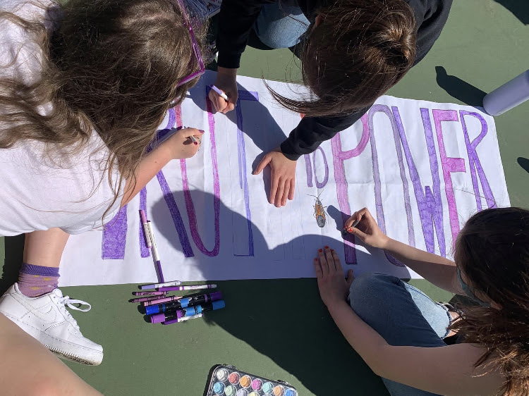 Three high schoolers drawing a Truth to Power banner