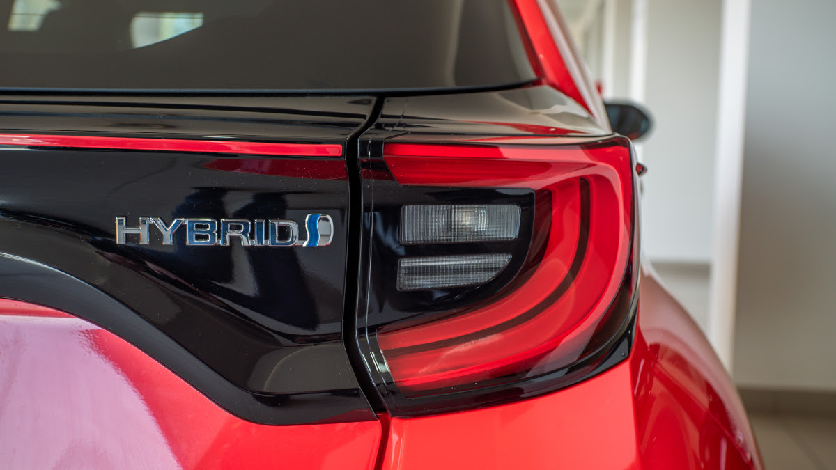 Closeup of a Toyota Yaris car's rear brake light next to the hybrid emblem.