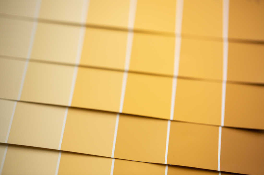 Paint swatches showing colors from light yellow to dark yellow are lined up and photographed from above, to represent the varying shades of yellow in urine.