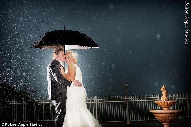 In love: A couple embrace beneath an umbrella, seemingly  oblivious to the rainstorm whipping up around them