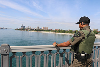 conservation officer standing on bridge looking over Detroit River