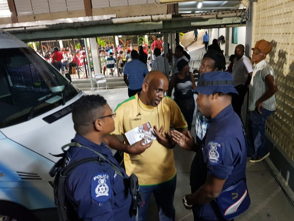 Police officers caution OWTU member Nigel White at the PNM meeting in Pt Fortin on Thursday night.