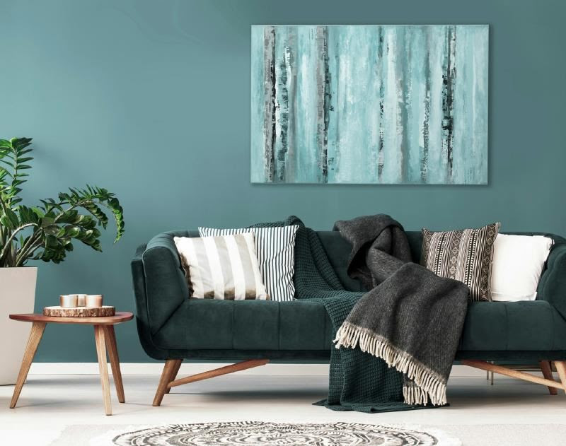 A couch with pillows and a painting on the wall Description automatically generated