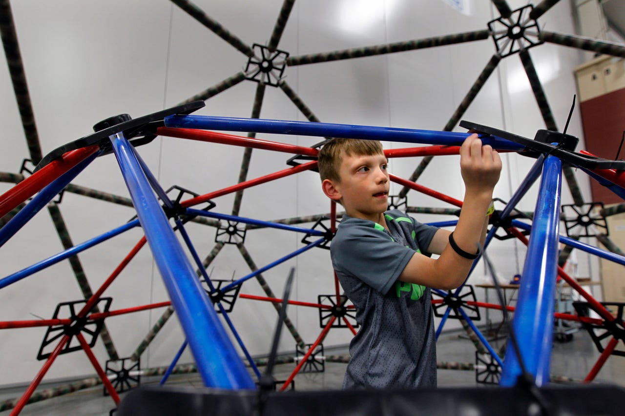 Josh Larsen, 8, of Franklin works in the Geodesic Dome on Saturday while attending the Maker Faire at State Fair Park. Andrew Cegielski, a representative of MKE Domes, said putting together this structure is a teaching tool for children that gives them a chance to have fun while learning at the same time.  More than 200 inventors were on hand to showcase their ideas at the event, which allows inventors and artists to swap ideas and show their work to the public.