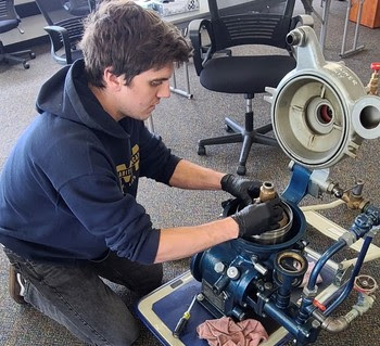 A new engine room employee reassembles a fuel oil purifier during training.