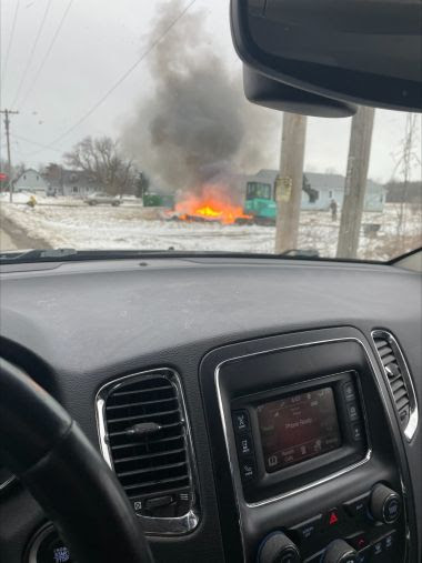 View from inside a vehicle, looking out at burning pile of trash
