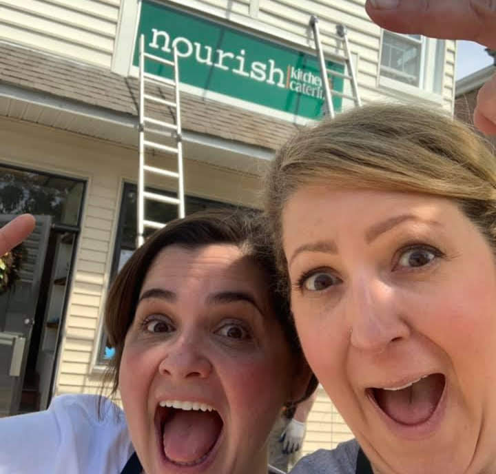 Owners of Nourish in front of sign