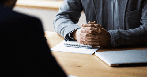 Man with hands folded sitting across from employer