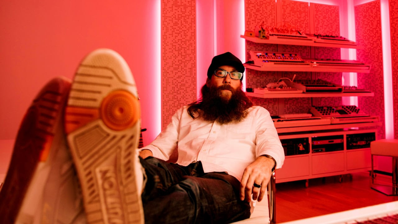Contemporary Christian music artist David Crowder sits in a chair at a mixing board in a studio