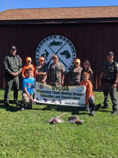 ECOs and youth hunters hold banner and show off hunting success during event