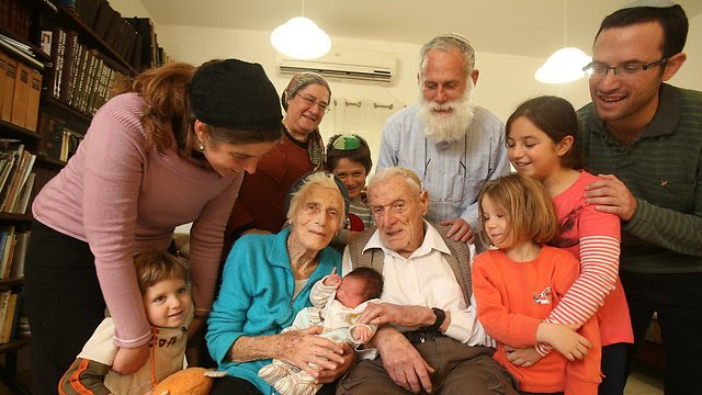 Michael and Marion Mittwochs, center, surrounded by family and holding their 100th great-granchild. (Photo: Elad Gershgoren) Photo