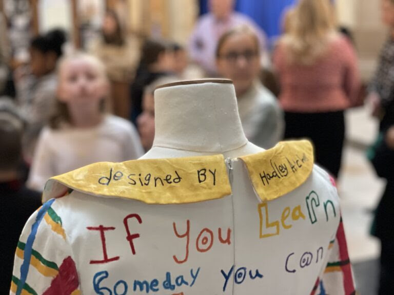 Image of Porucho's dress, colorful with handwritten credit from a student on it 