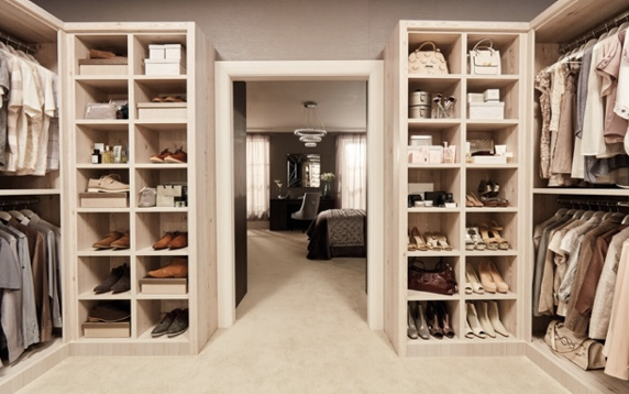 a beige and cream wooden boutique dressing room featuring lots of clothes, shoes and bags as a way to store clothes