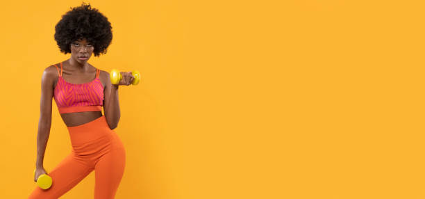 Fitness instructor with dumbels. Fitness instructor with dumbels on orange background. sexy slim fit ladies stock pictures, royalty-free photos & images